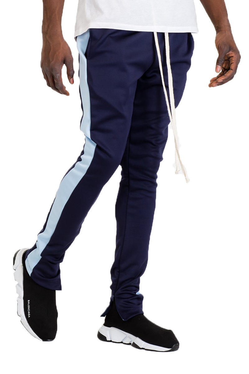 A pair of black skinny fit track pants featuring a single stripe detail, tug-free zipper closure, and hidden ankle zipper, displayed on a model.