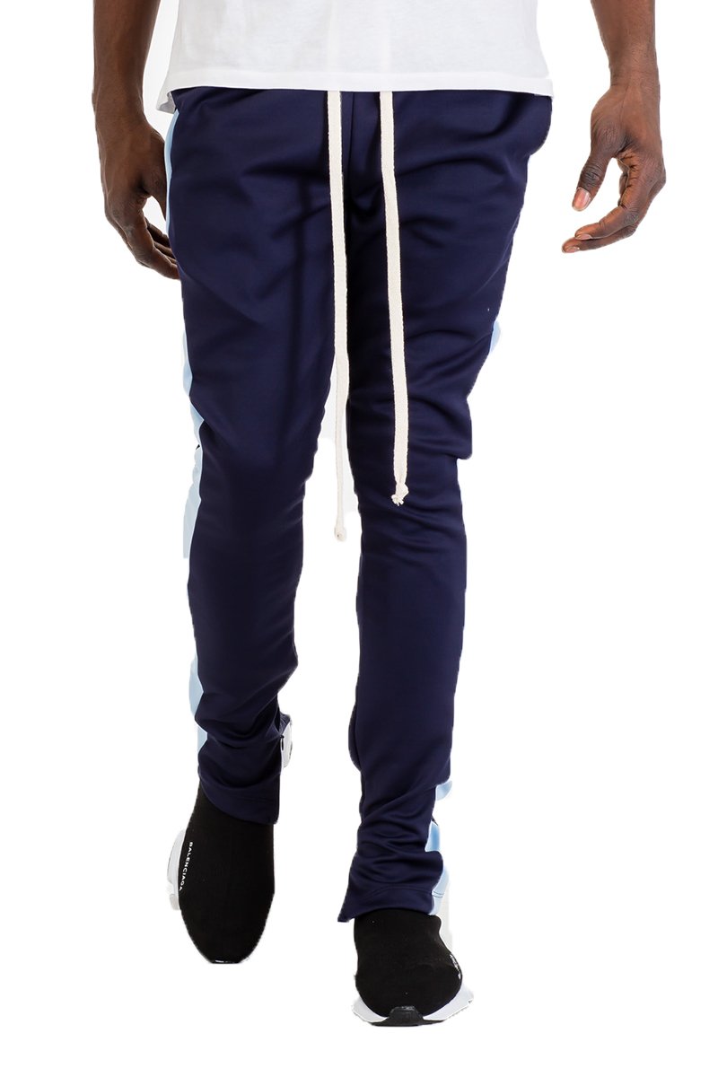 A pair of black skinny fit track pants featuring a single stripe detail, tug-free zipper closure, and hidden ankle zipper, displayed on a model.