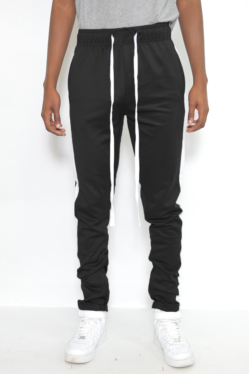 A pair of black and white slim fit track pants featuring hidden ankle zippers and standard pockets, designed for comfort and style.