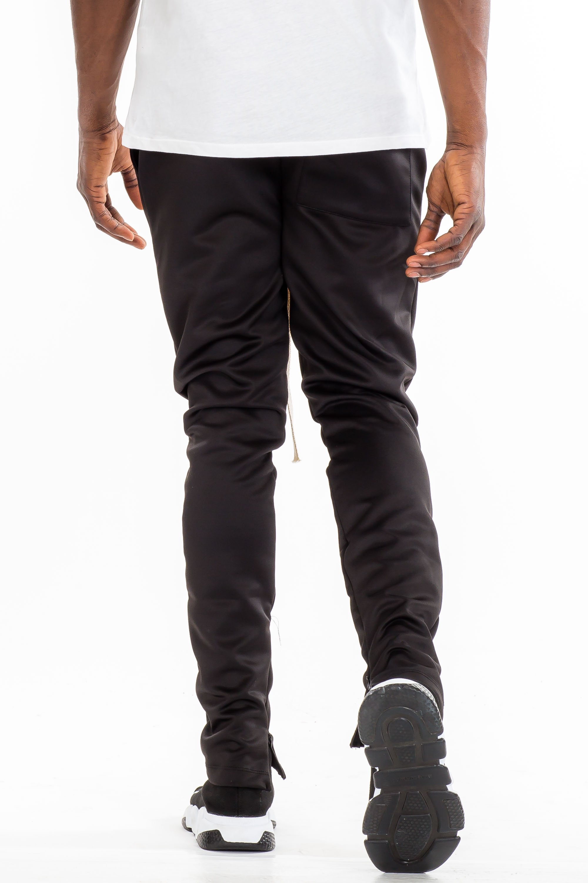 A pair of stylish solid track pants featuring a skinny fit, elastic waist with drawstring, and hidden ankle zippers, displayed on a neutral background.