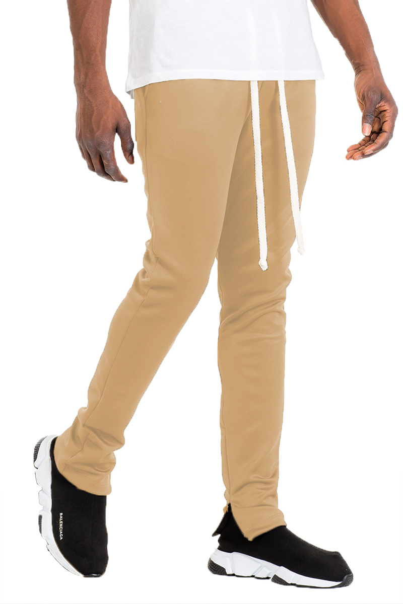 A pair of stylish solid track pants featuring a skinny fit, elastic waist with drawstring, and hidden ankle zippers, displayed on a mannequin.