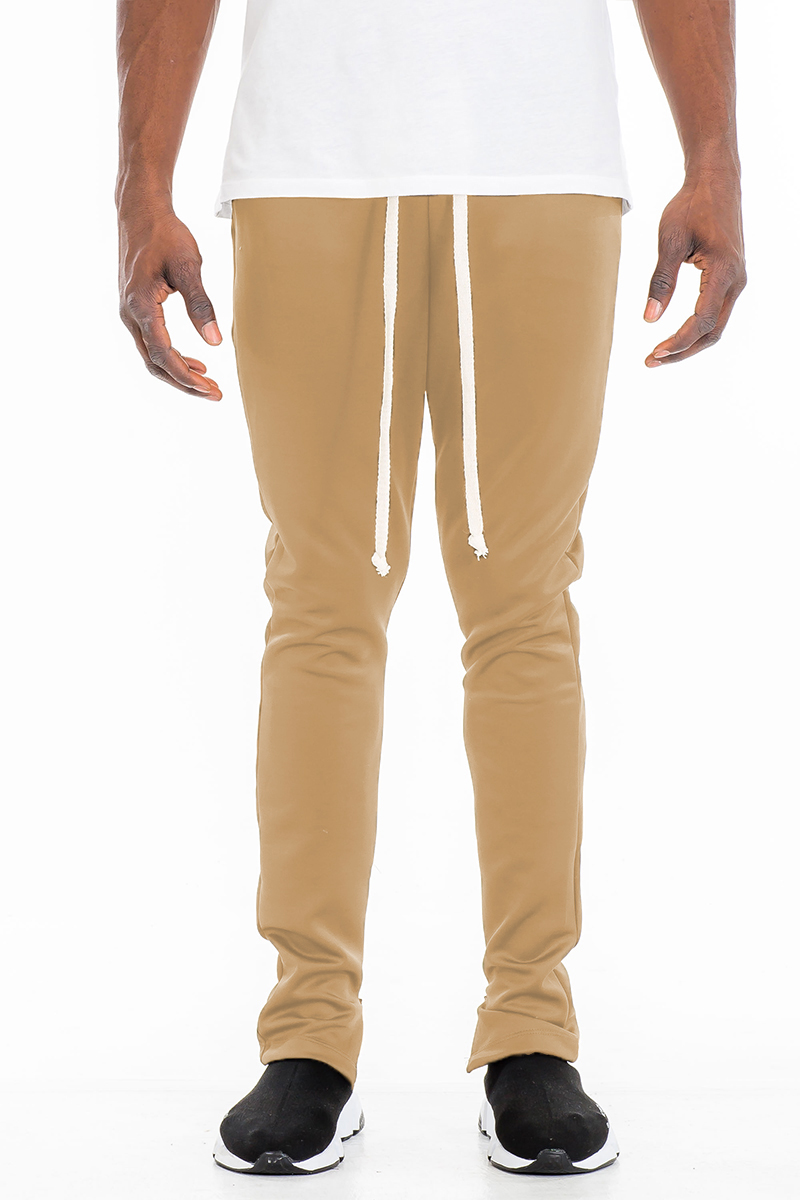 A pair of stylish solid track pants featuring a skinny fit, elastic waist with drawstring, and hidden ankle zippers, displayed on a mannequin.