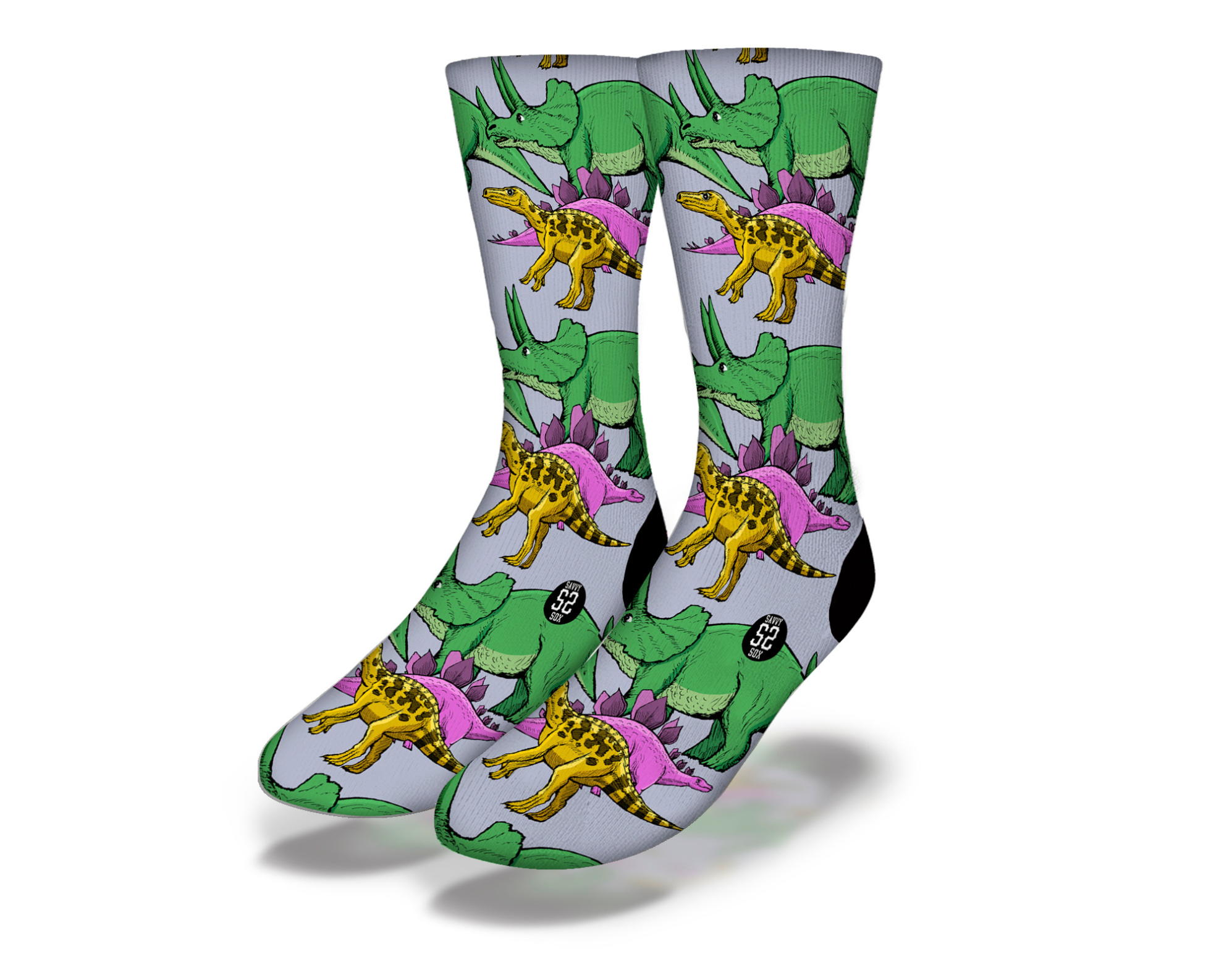 A pair of colorful BAD TO THE BONE STOMPING DINOS socks featuring a yellow T-Rex, purple Stegosaurus, and green Triceratops designs.