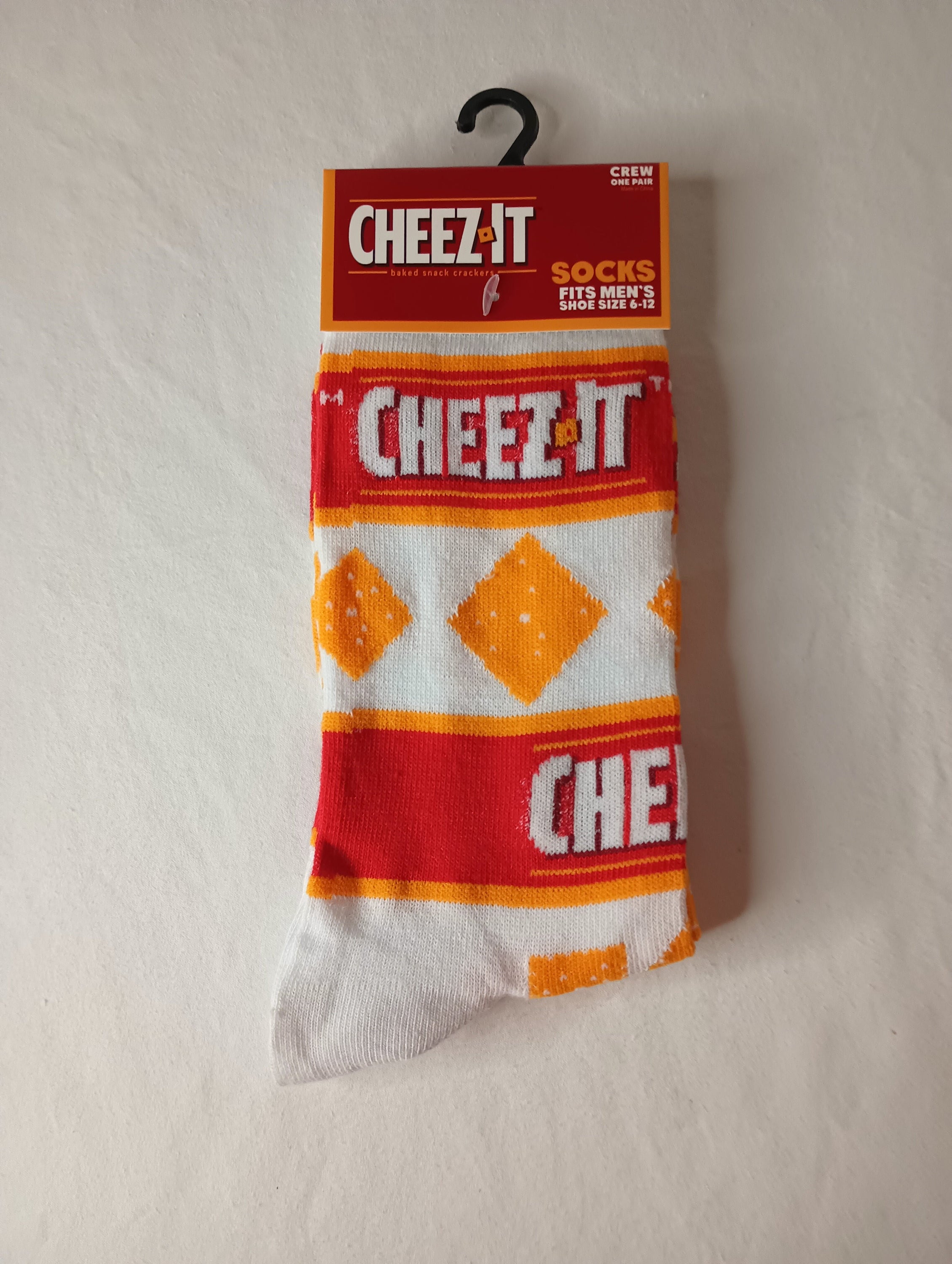 A pair of vibrant CHEEZ-IT Crew Socks in orange, white, and red colors, designed for men's shoe sizes 6-12.