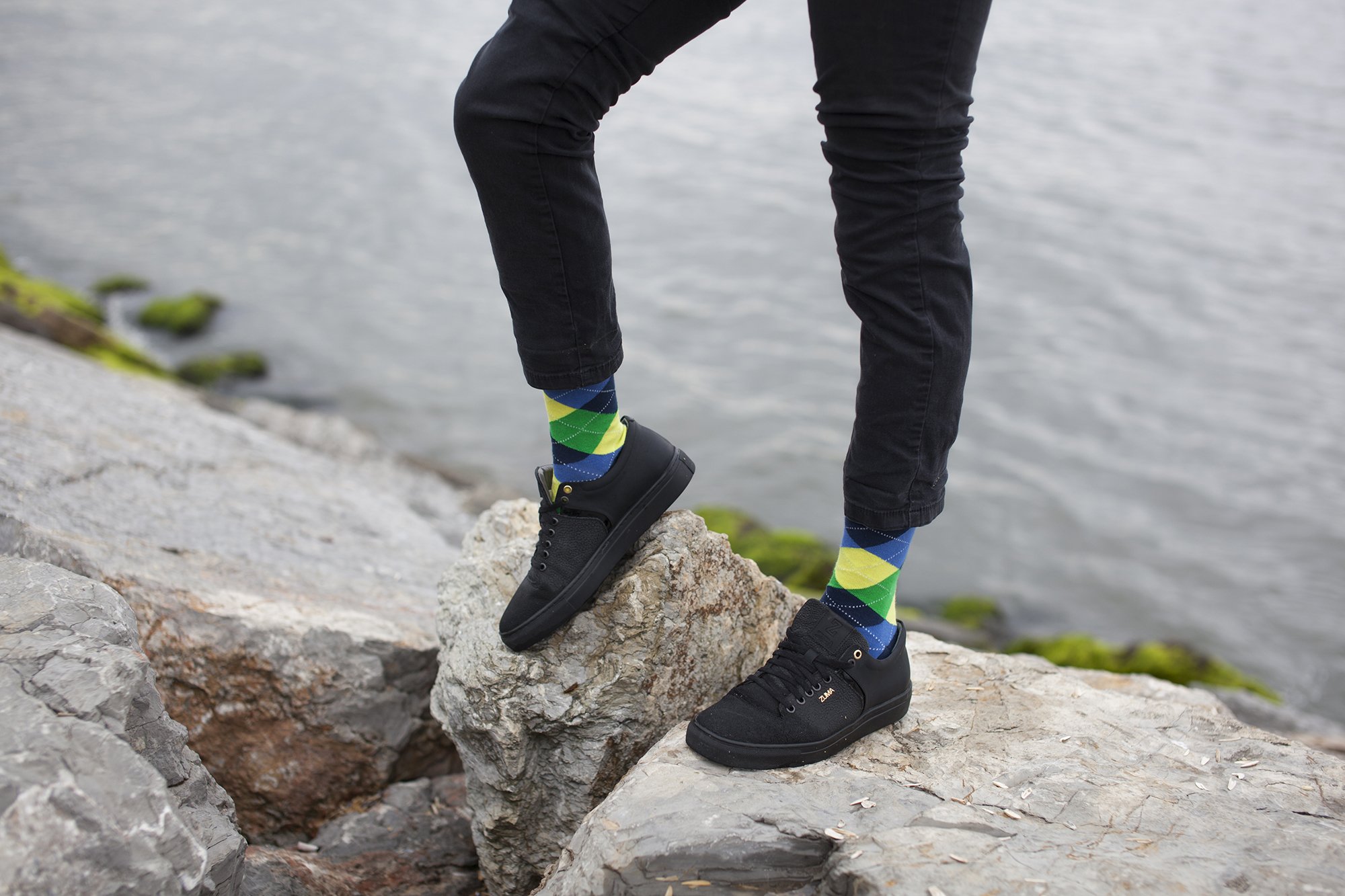 Person standing on rocks by water.