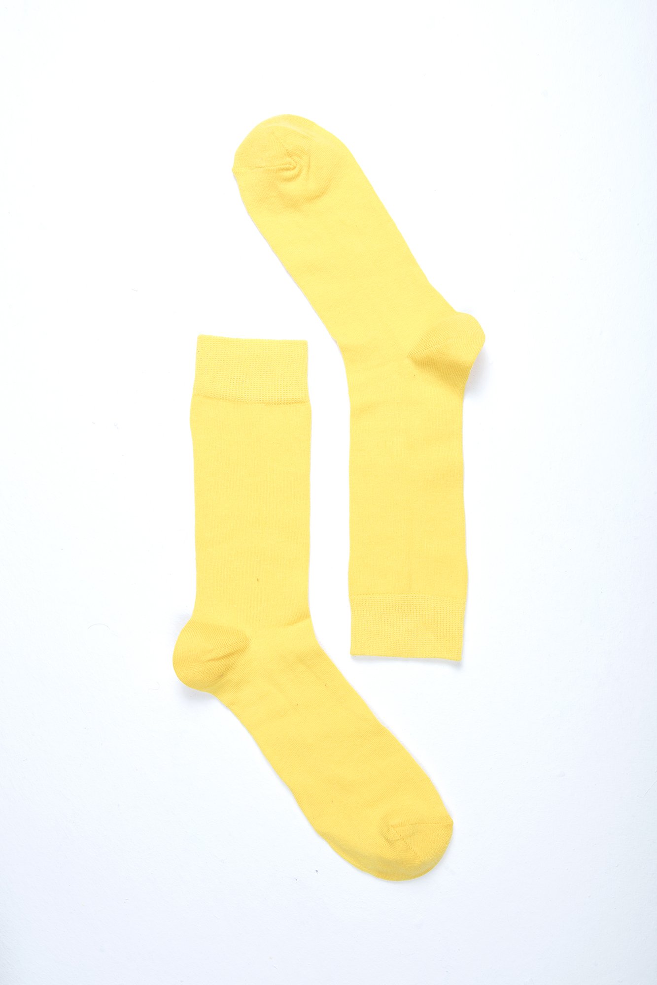 A pair of vibrant men's solid yellow socks made from soft Turkish cotton, showcasing a trendy and stylish design.