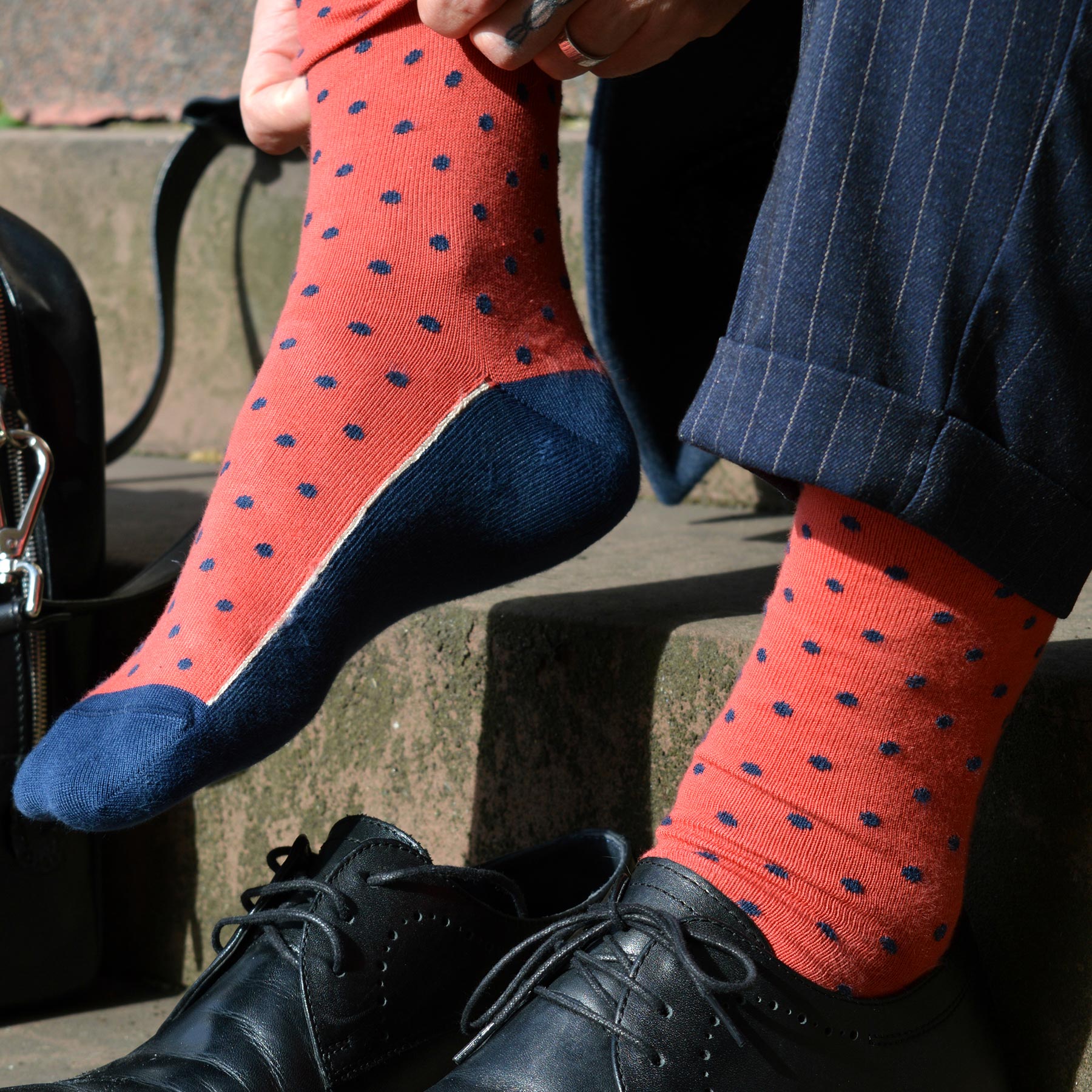 A pair of vibrant apple-colored men's socks with polka dots, featuring contrasting cuffs, heels, and toes, made from luxurious Supima cotton.