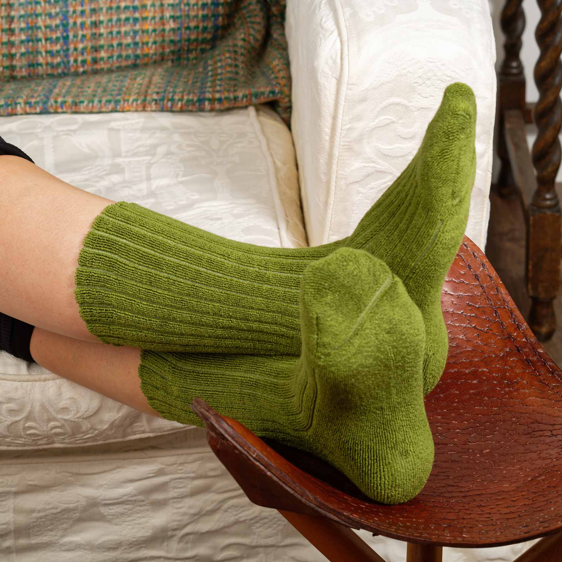 A pair of green ribbed women's bed socks, showcasing a fluffy texture and seamless toe design, perfect for cozy winter lounging.