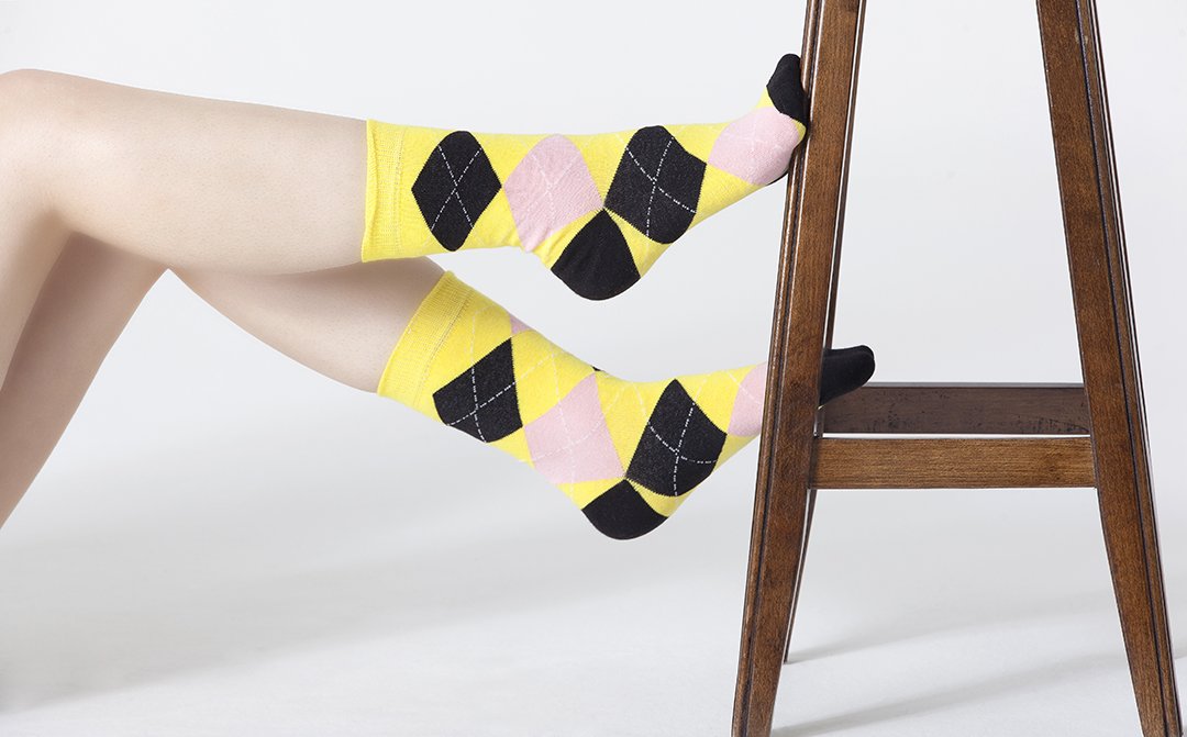 A pair of Women's Black Pineapple Argyle Socks featuring a vibrant pineapple pattern on a black background, perfect for adding a fun touch to any outfit.