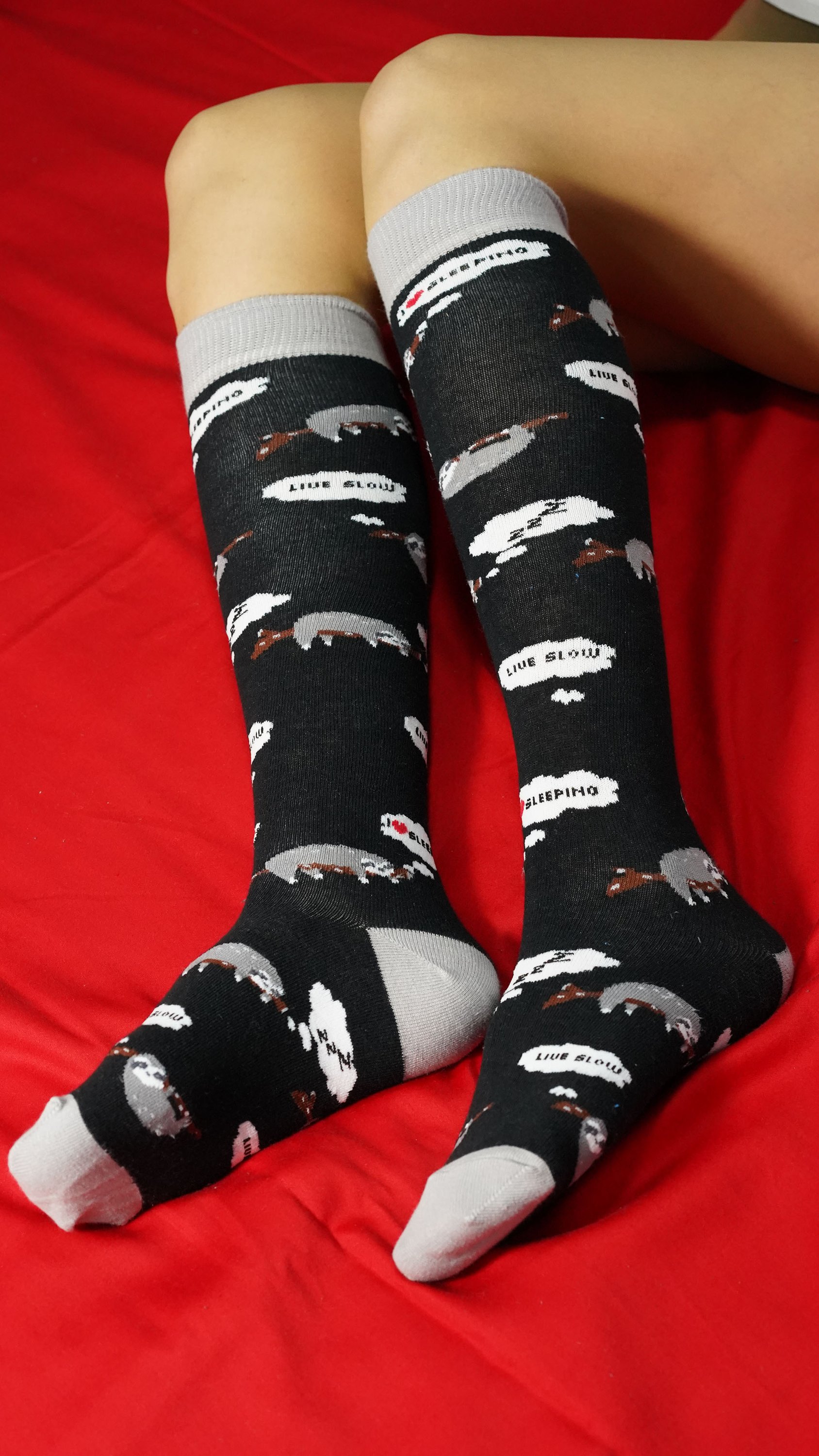 A pair of Women's Lazy Sloth Knee High Socks featuring a colorful sloth design, made from soft Turkish cotton for comfort and style.