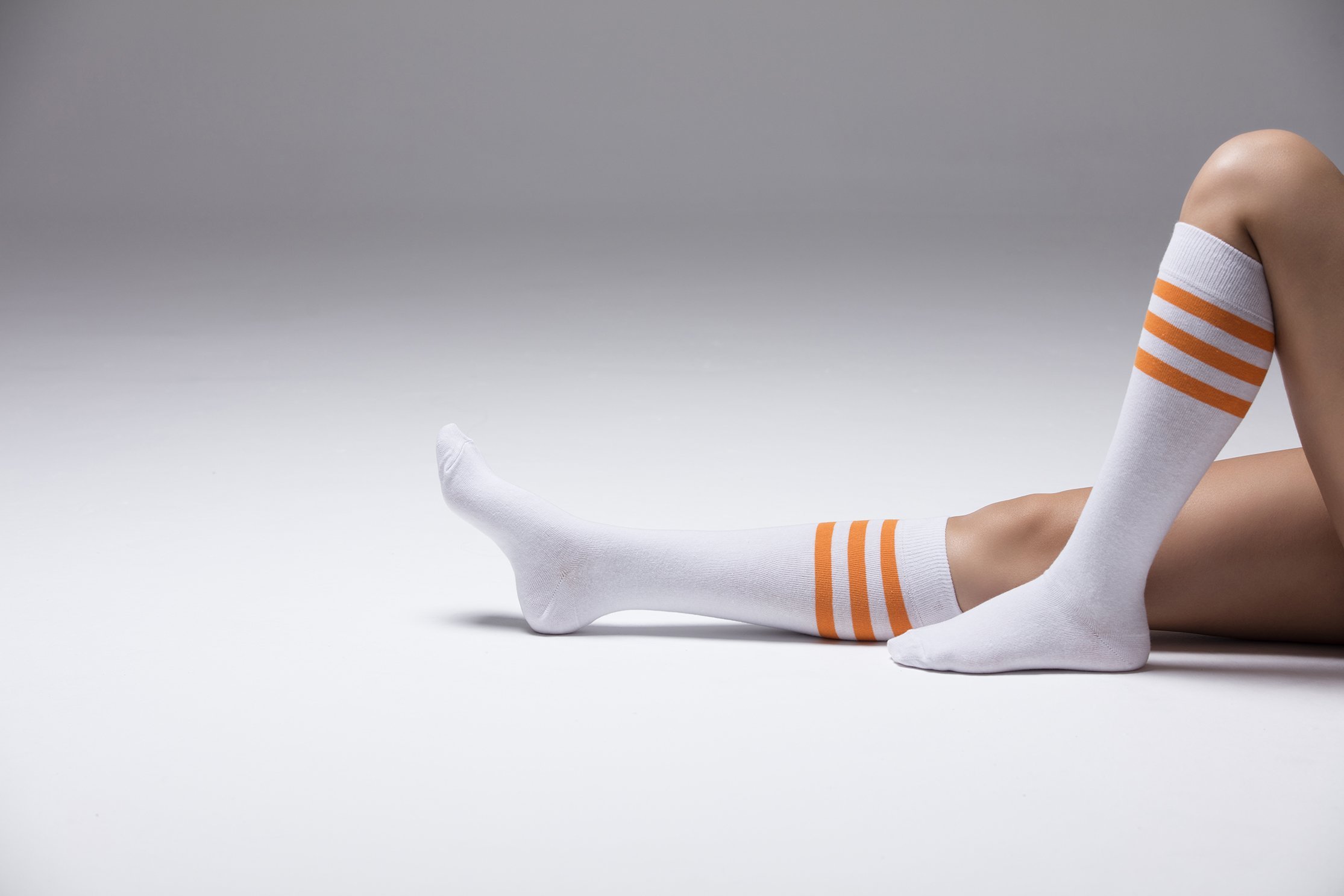 A pair of vibrant women's knee-high socks featuring solid orange stripes, showcasing their stylish design and comfortable fit.