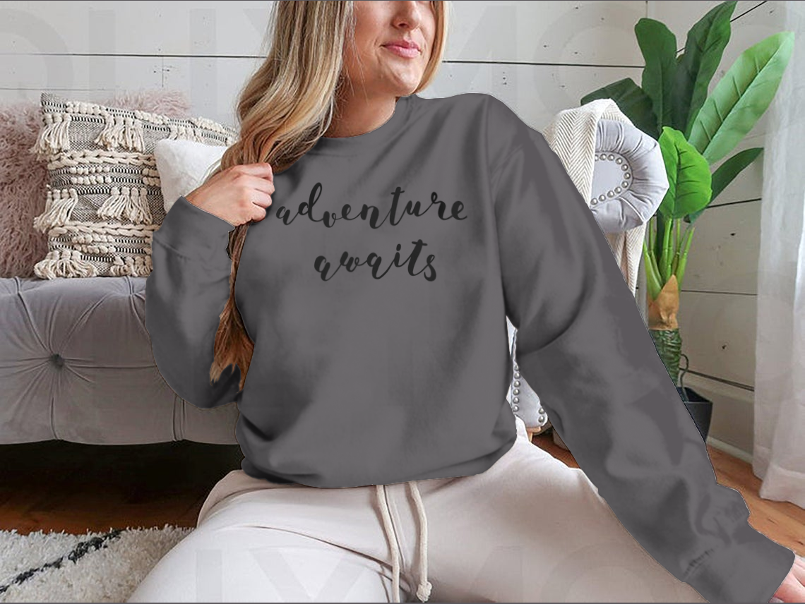 A stylish cotton-polyester blend shirt featuring the inspiring quote 'Adventure Awaits' in beautiful hand lettering, perfect for motivation.