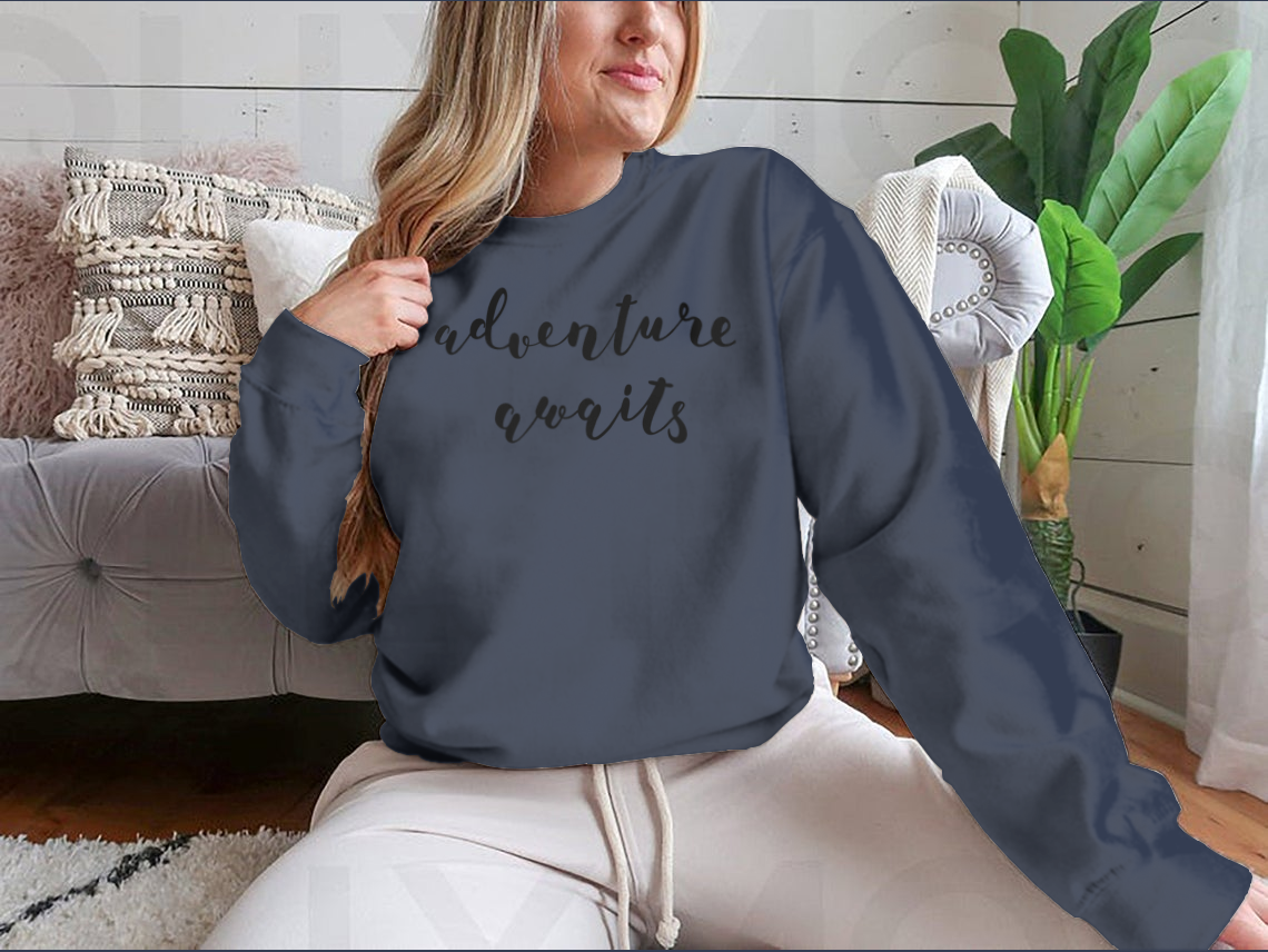 A stylish cotton-polyester blend shirt featuring the inspiring quote 'Adventure Awaits' in beautiful hand lettering, perfect for motivation.