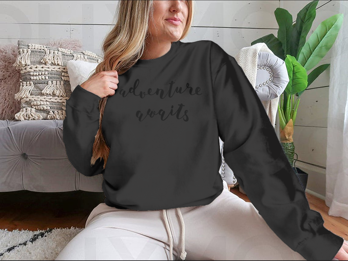 A stylish cotton-polyester blend shirt featuring the inspiring quote 'Adventure Awaits' in beautiful hand lettering, perfect for motivation.