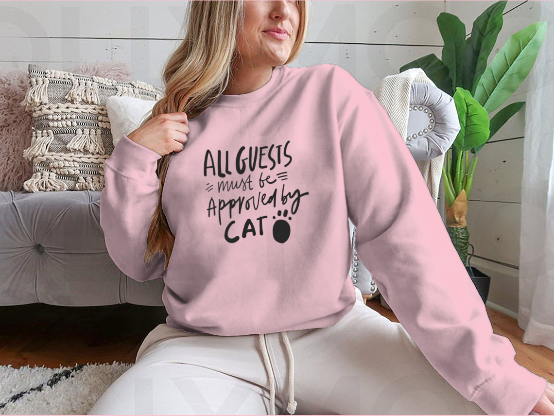 A humorous t-shirt featuring the quote 'All Guests Must Be Approved By Cat', showcasing a playful design for cat lovers.