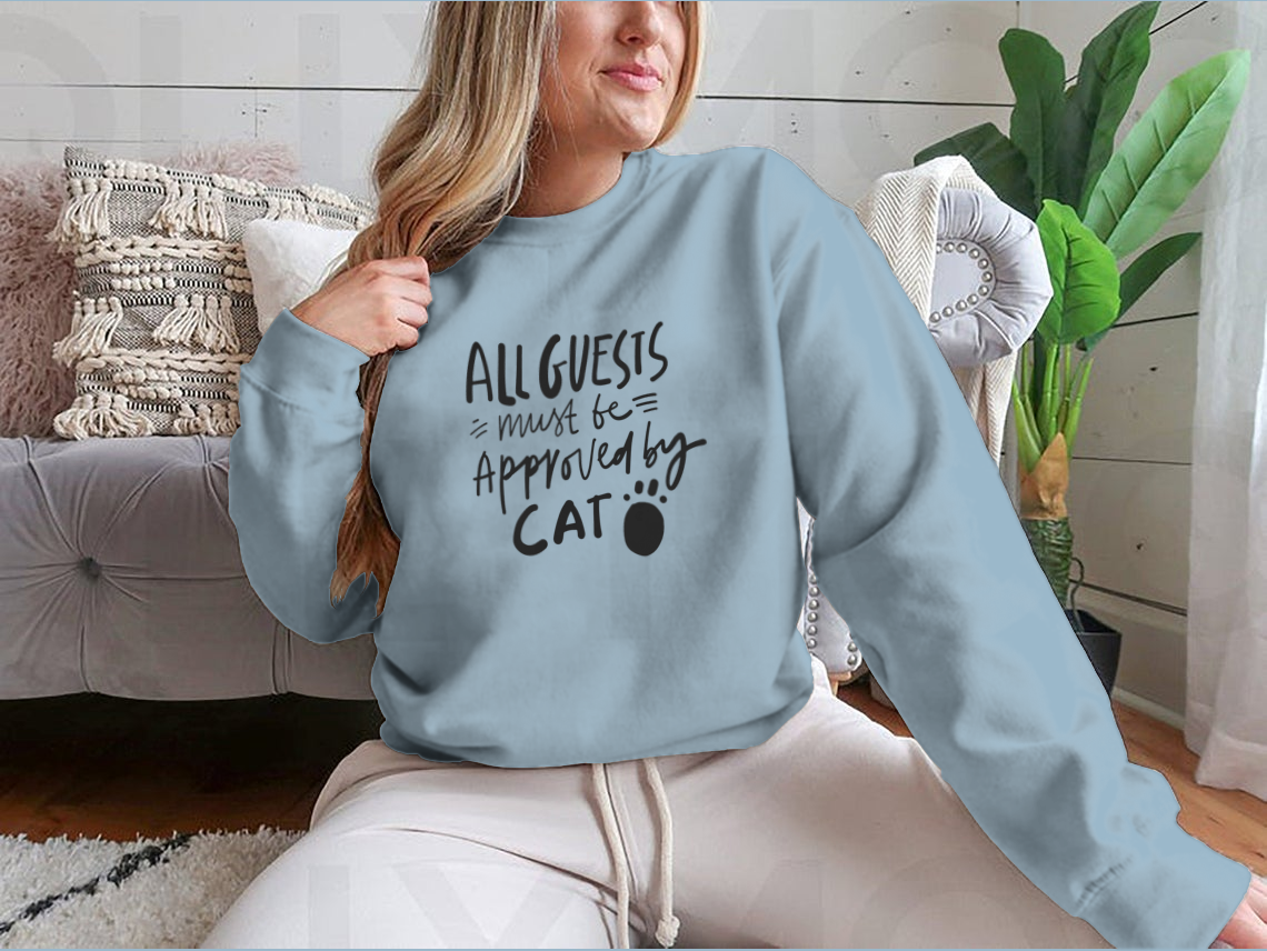 A humorous t-shirt featuring the quote 'All Guests Must Be Approved By Cat', showcasing a playful design for cat lovers.