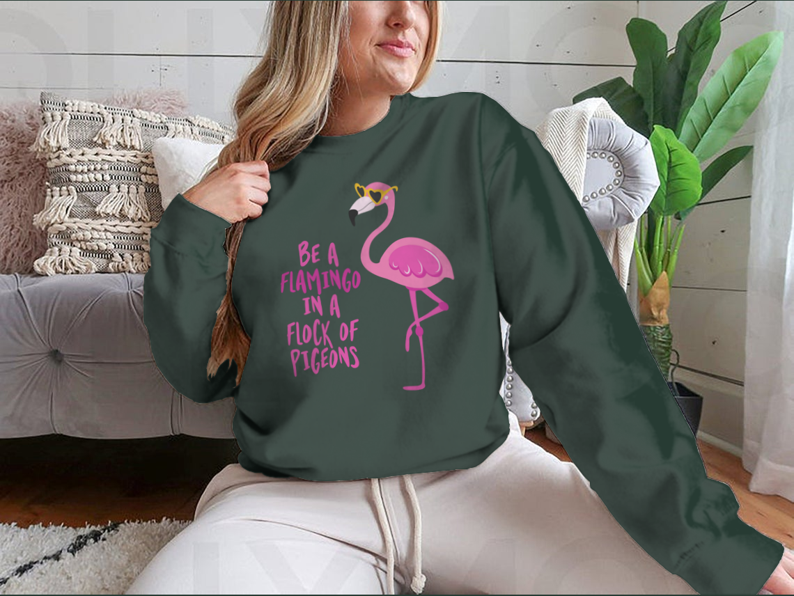 A stylish t-shirt featuring the motivational quote 'Be A Flamingo In A Flock Of Pigeons' in vibrant colors, made from high-quality cotton.