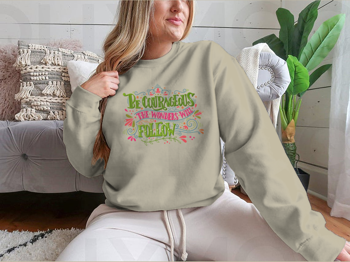 A motivational apparel piece featuring the phrase 'Be Courageous, The Wonders Will Follow' in a stylish design, made from a soft cotton/polyester blend.