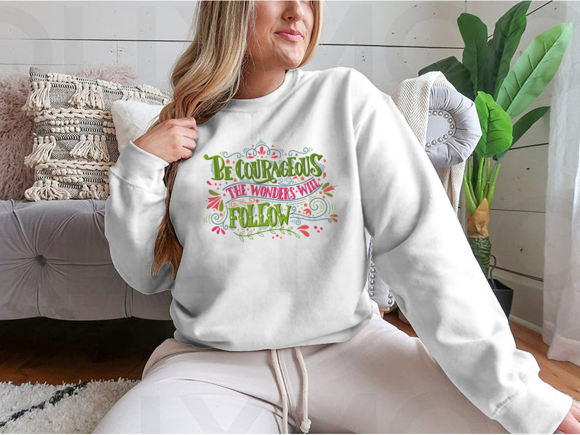 A motivational apparel piece featuring the phrase 'Be Courageous, The Wonders Will Follow' in a stylish design, made from a soft cotton/polyester blend.