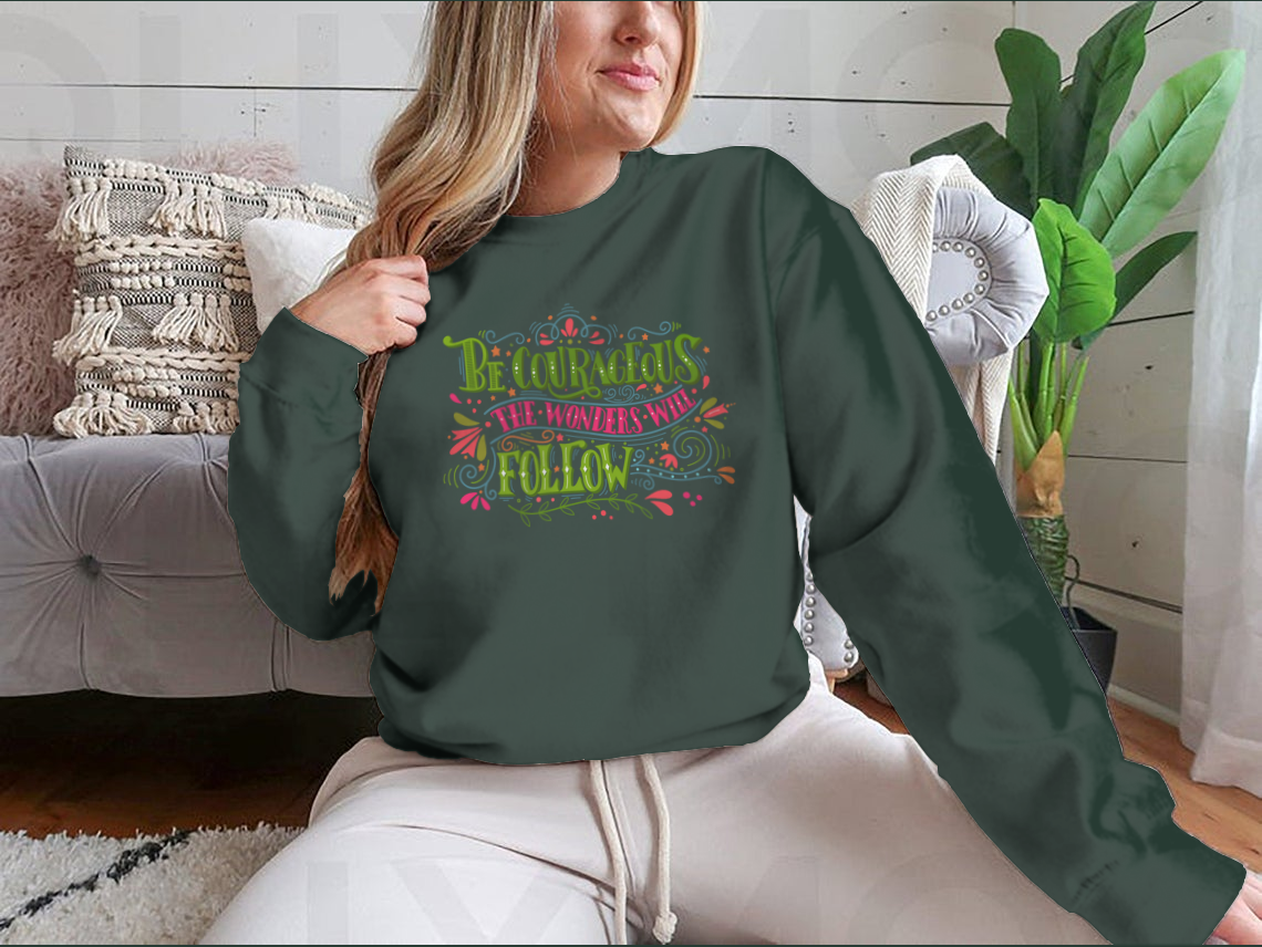 A motivational apparel piece featuring the phrase 'Be Courageous, The Wonders Will Follow' in a stylish design, made from a soft cotton/polyester blend.