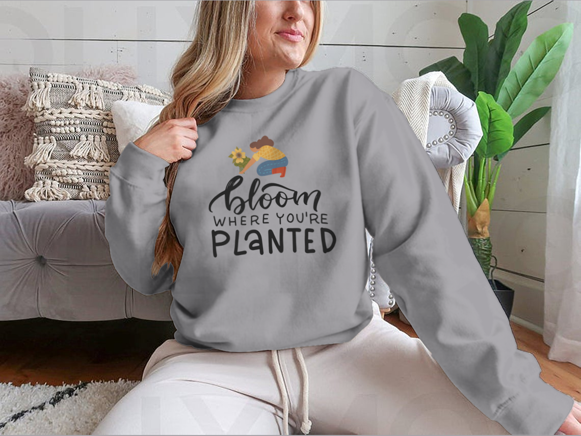 A stylish t-shirt featuring the hand-drawn quote 'Bloom Where You Are Planted' in elegant lettering.