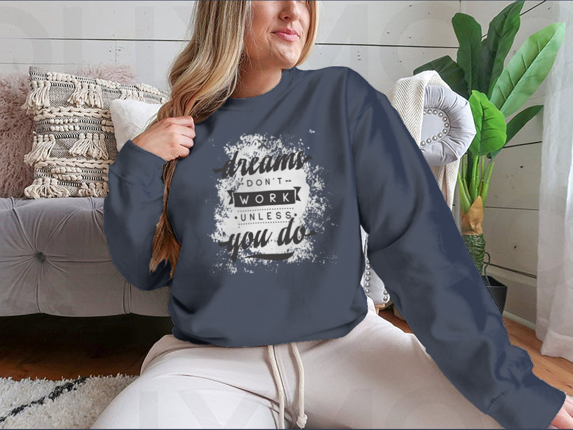 A cozy sweatshirt featuring the motivational phrase 'Dreams Don't Work Unless You Do', made from a soft cotton-polyester blend.