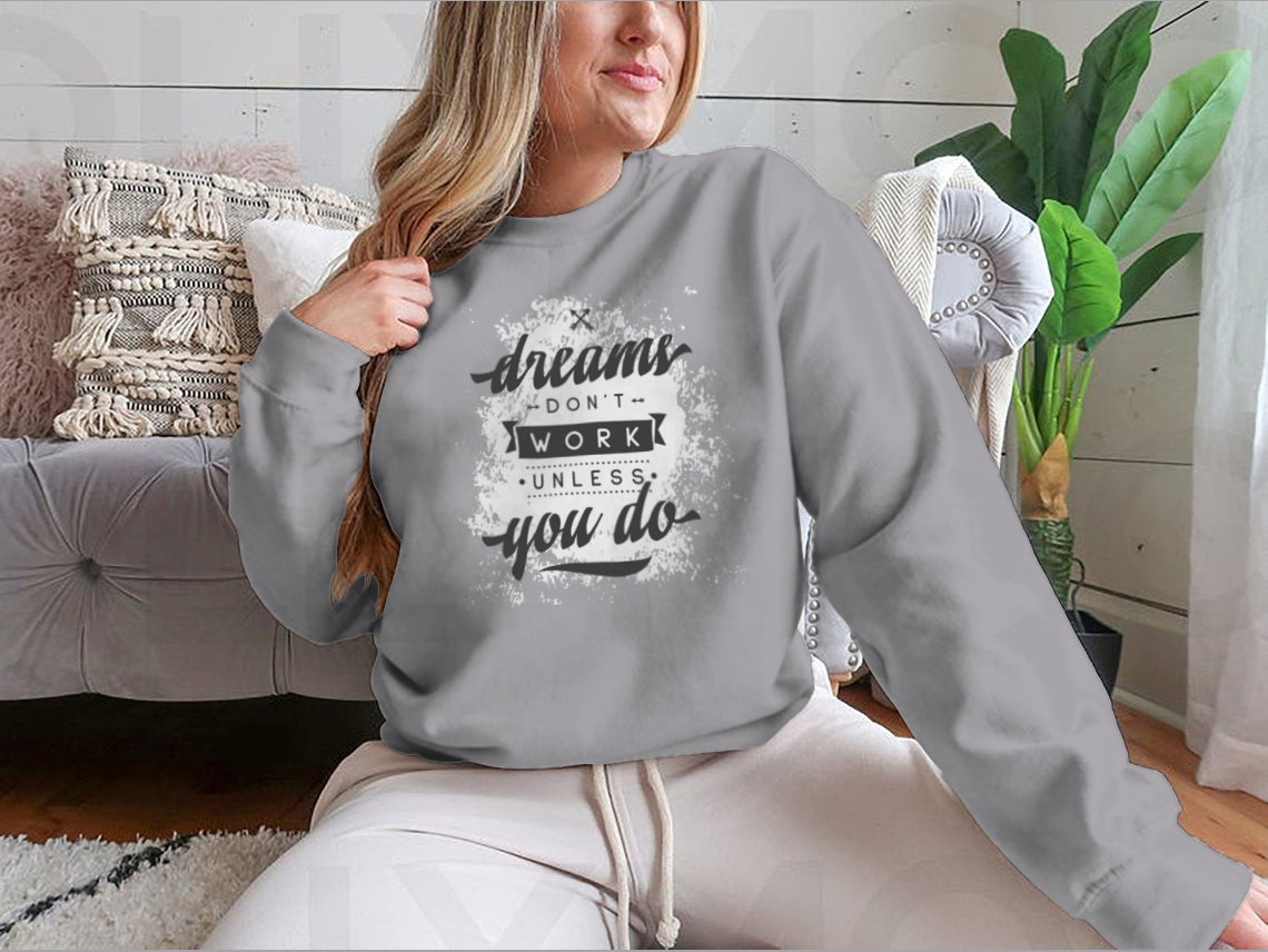 A cozy sweatshirt featuring the motivational phrase 'Dreams Don't Work Unless You Do', made from a soft cotton-polyester blend.