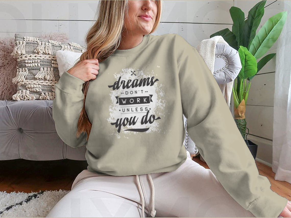 A cozy sweatshirt featuring the motivational phrase 'Dreams Don't Work Unless You Do', made from a soft cotton-polyester blend.