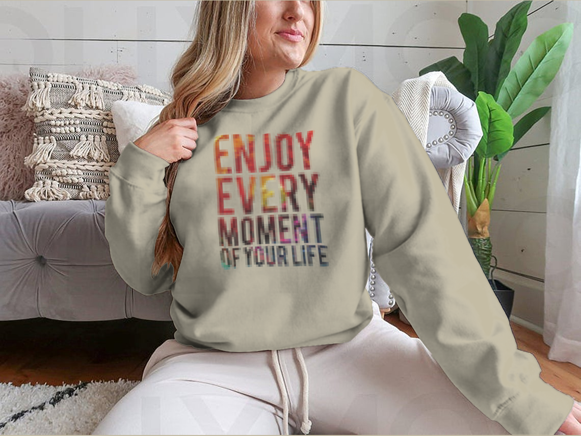 A motivational t-shirt featuring the phrase 'Enjoy Every Moment Of Your Life', made from a comfortable cotton/polyester blend.