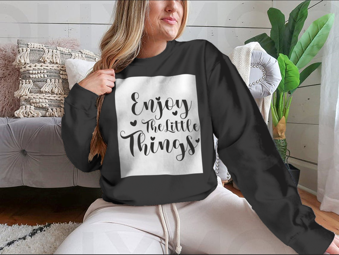 A cozy sweatshirt featuring the calligraphy design 'Enjoy The Little Things', showcasing its soft fabric and classic fit.