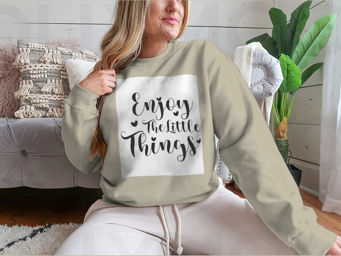 A cozy sweatshirt featuring the calligraphy design 'Enjoy The Little Things', showcasing its soft fabric and classic fit.