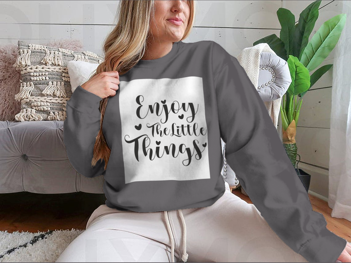 A cozy sweatshirt featuring the calligraphy design 'Enjoy The Little Things', showcasing its soft fabric and classic fit.