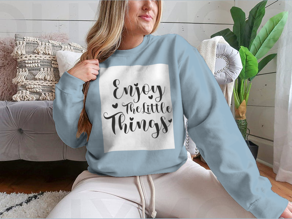 A cozy sweatshirt featuring the calligraphy design 'Enjoy The Little Things', showcasing its soft fabric and classic fit.