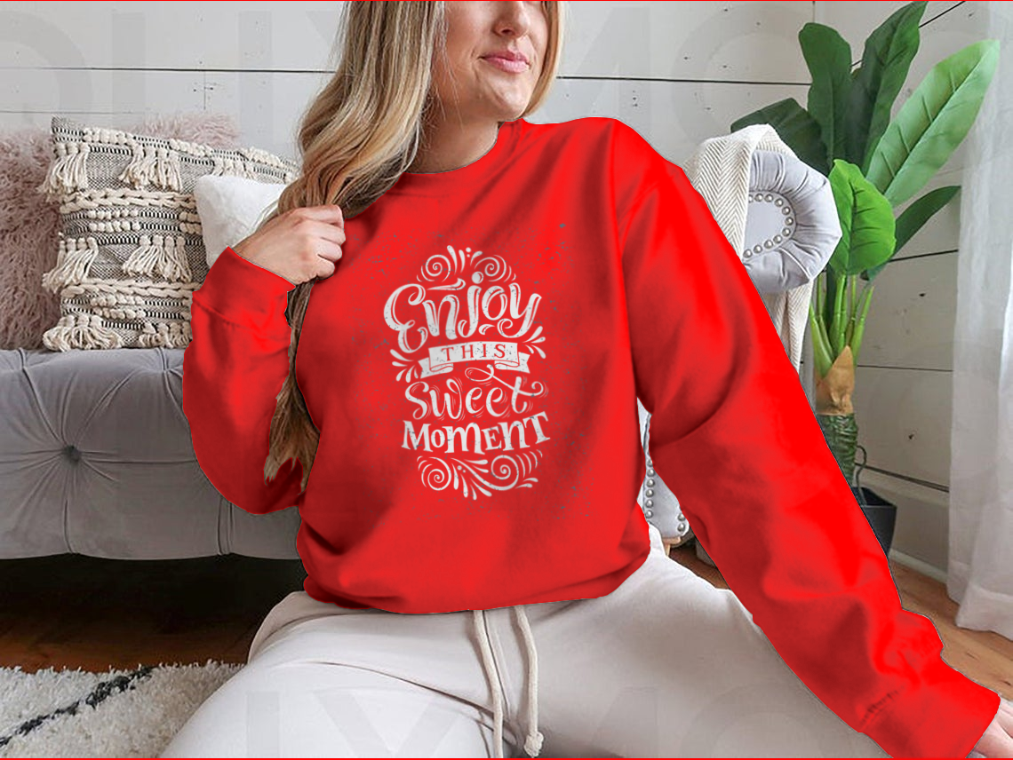 A cozy sweatshirt featuring the phrase 'Enjoy This Sweet Moment' in stylish typography, made from a soft cotton/polyester blend.