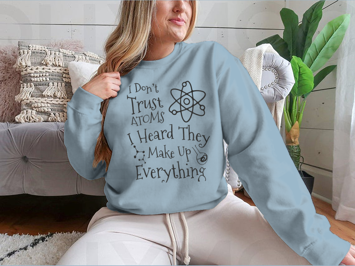 A humorous t-shirt featuring the phrase 'I Don't Trust Atoms I Heard They Make Up Everything' in a stylish design, perfect for science enthusiasts.