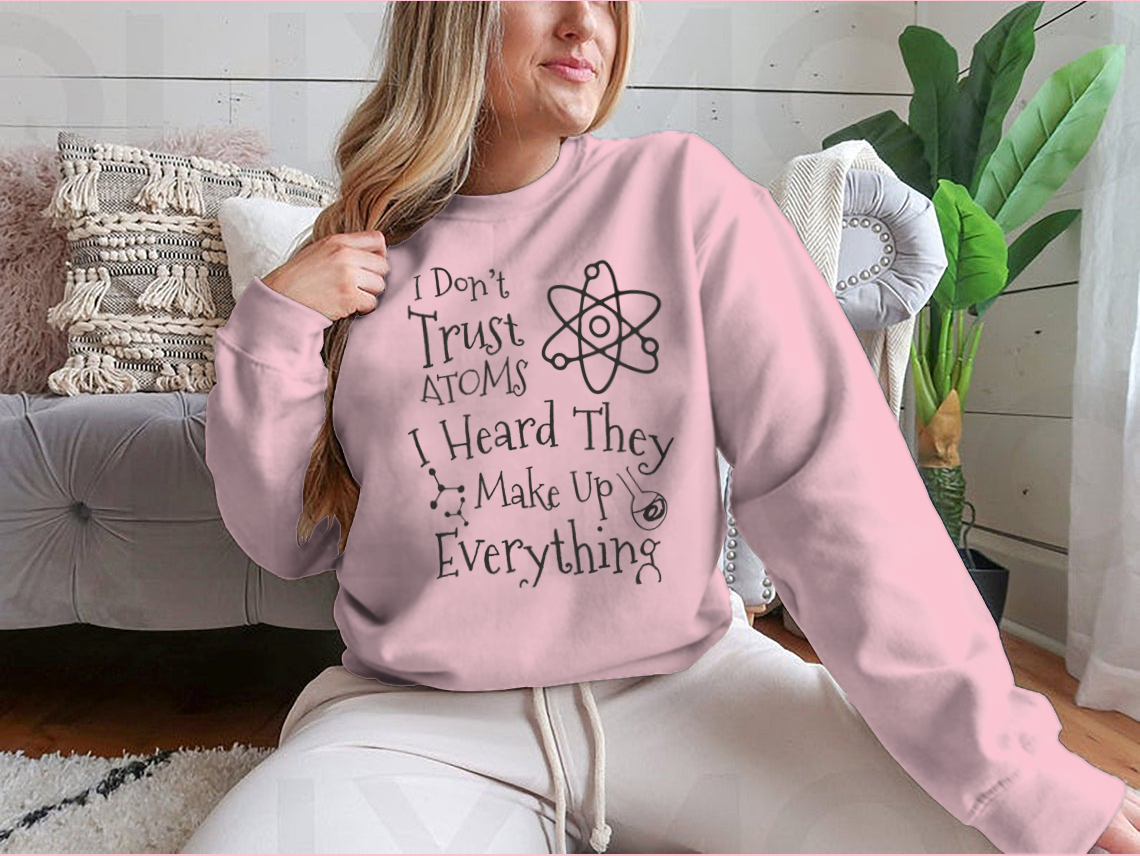 A humorous t-shirt featuring the phrase 'I Don't Trust Atoms I Heard They Make Up Everything' in a stylish design, perfect for science enthusiasts.