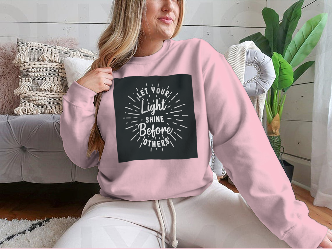 A stylish hand lettering typography shirt with the phrase 'Let Your Light Shine Before Others' displayed prominently, made from soft cotton fabric.