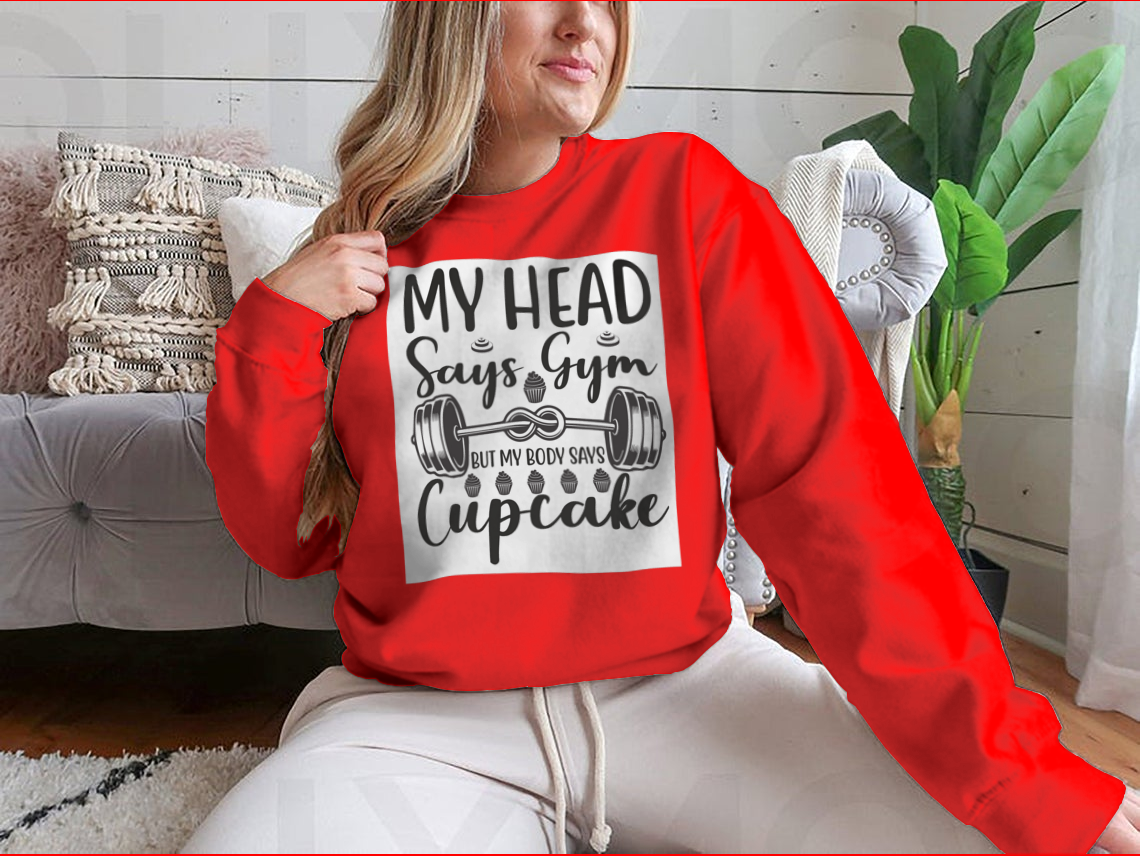 A cozy sweatshirt featuring the phrase 'My Head Says Gym But My Body Says Cupcake' in a playful font, perfect for casual wear.