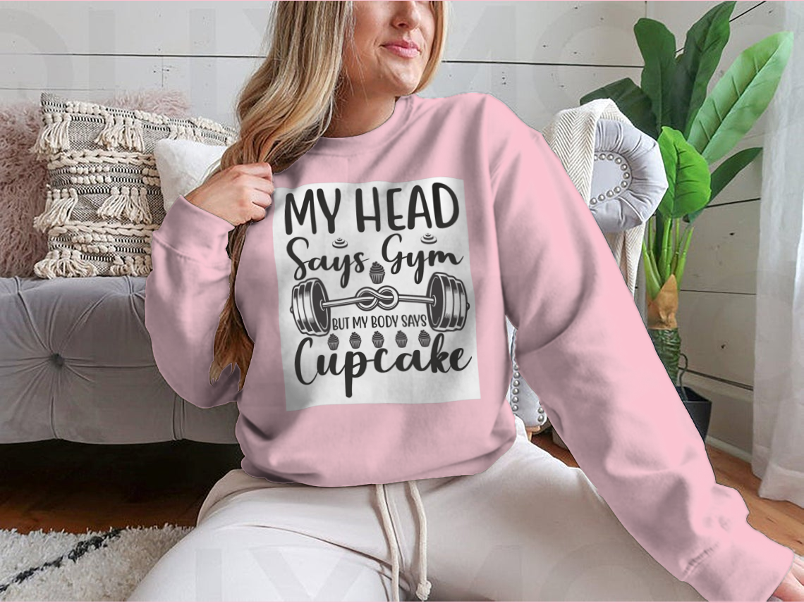 A cozy sweatshirt featuring the phrase 'My Head Says Gym But My Body Says Cupcake' in a playful font, perfect for casual wear.