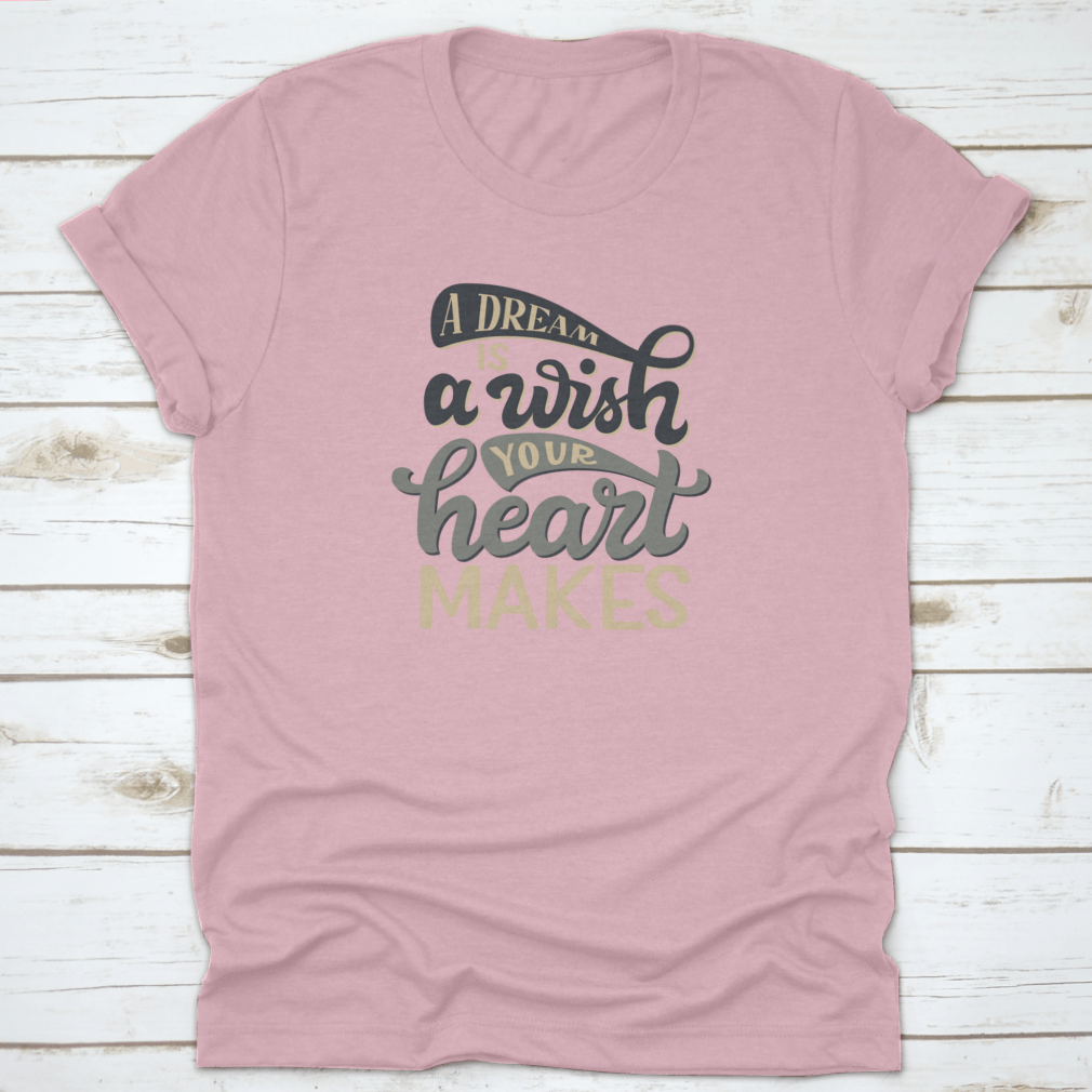 A stylish t-shirt featuring the hand-drawn quote 'A Dream Is A Wish Your Heart Makes' in elegant typography, made from soft cotton fabric.