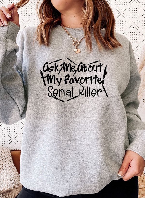 A cozy black sweatshirt featuring the phrase 'Ask Me About My Favorite Serial Killer' in bold white letters, perfect for casual wear.