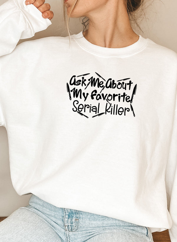 A cozy black sweatshirt featuring the phrase 'Ask Me About My Favorite Serial Killer' in bold white letters, perfect for casual wear.