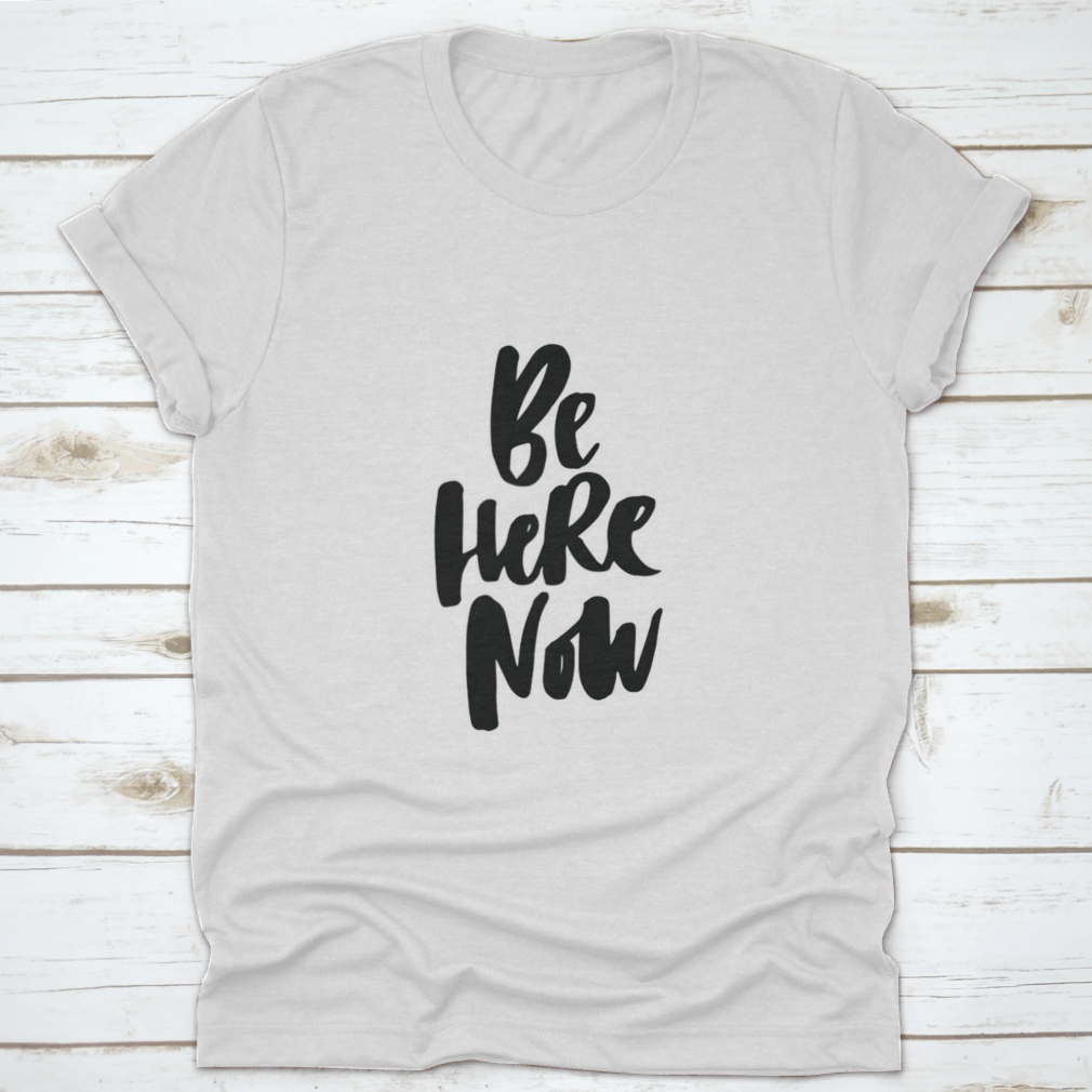 Be Here Now T-Shirt featuring hand-drawn brush pen lettering design on a soft cotton fabric.