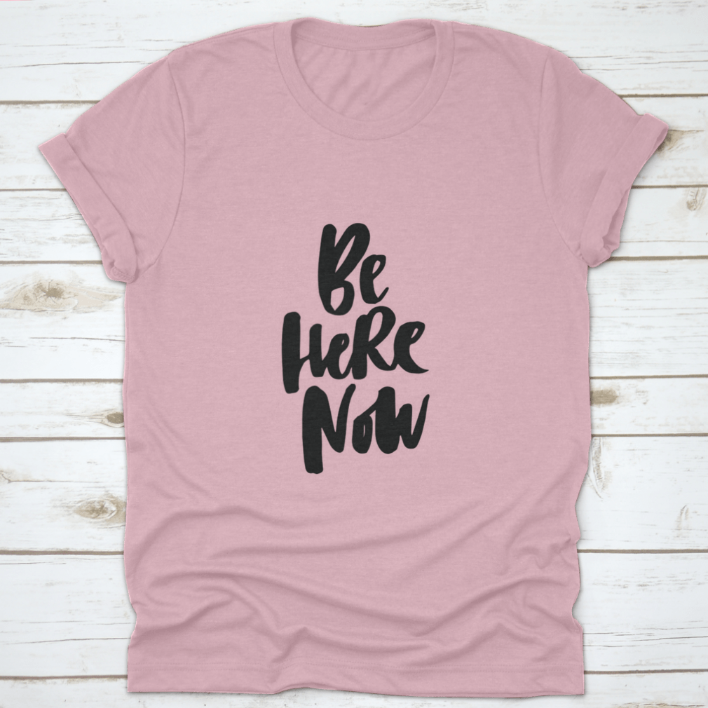 Be Here Now T-Shirt featuring hand-drawn brush pen lettering design on a soft cotton fabric.