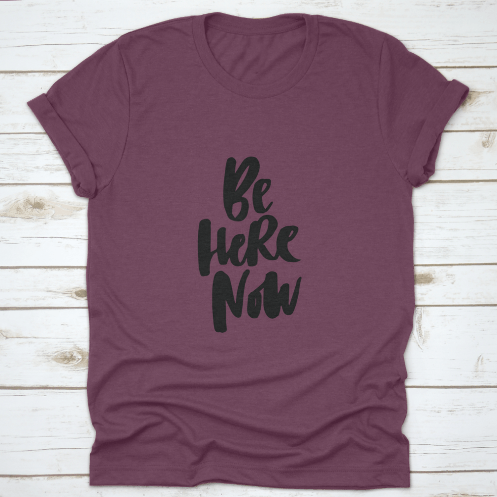 Be Here Now T-Shirt featuring hand-drawn brush pen lettering design on a soft cotton fabric.