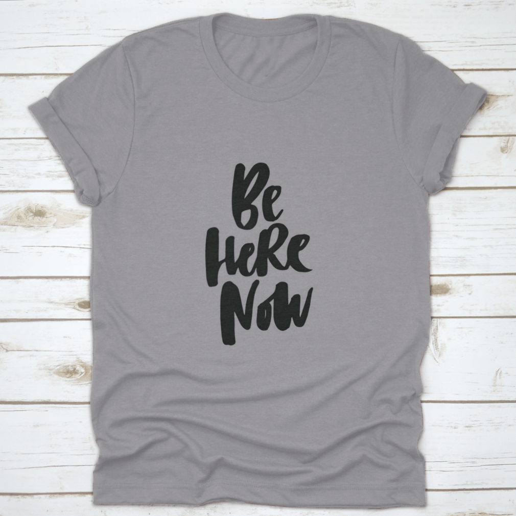 Be Here Now T-Shirt featuring hand-drawn brush pen lettering design on a soft cotton fabric.