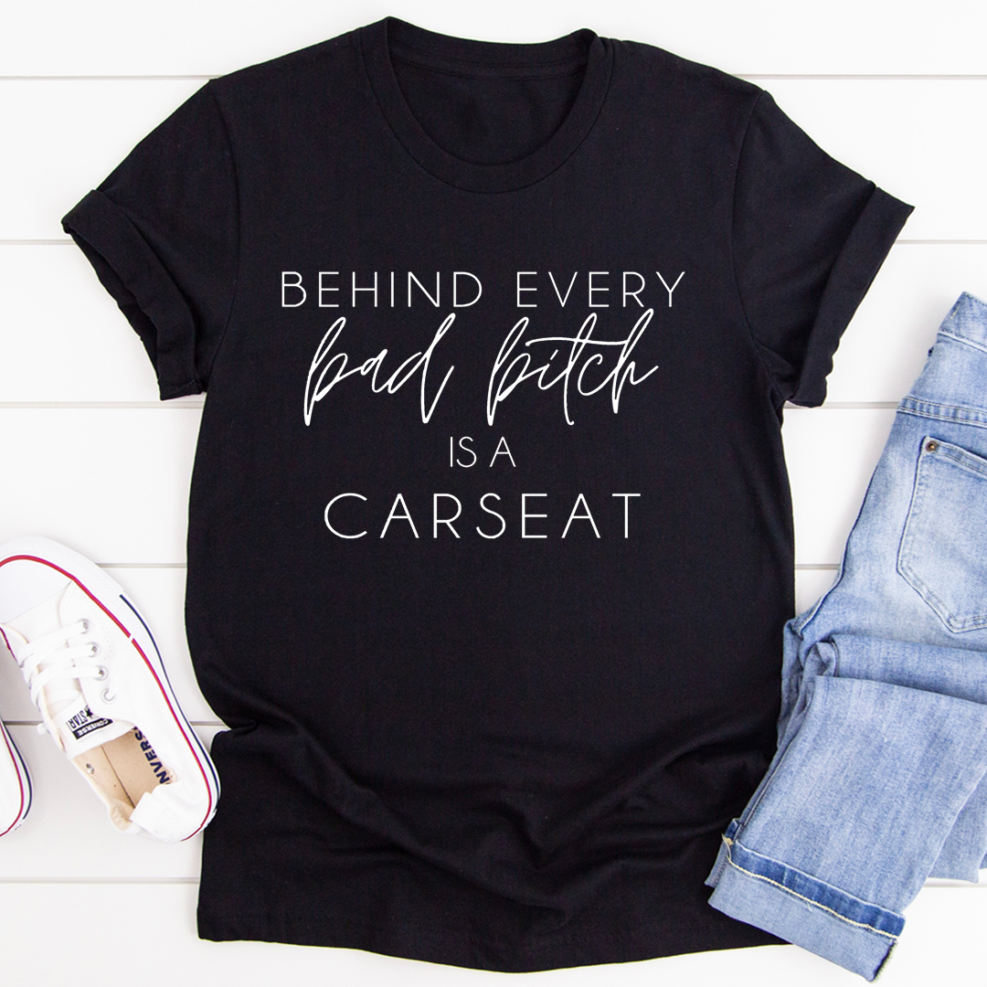 A stylish t-shirt featuring the phrase 'Behind Every Bad B Is A Car Seat', made from soft ring-spun cotton with double stitching.