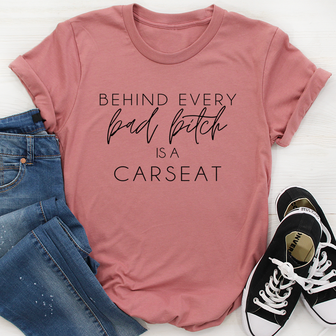 A stylish t-shirt featuring the phrase 'Behind Every Bad B Is A Car Seat', made from soft ring-spun cotton with double stitching.