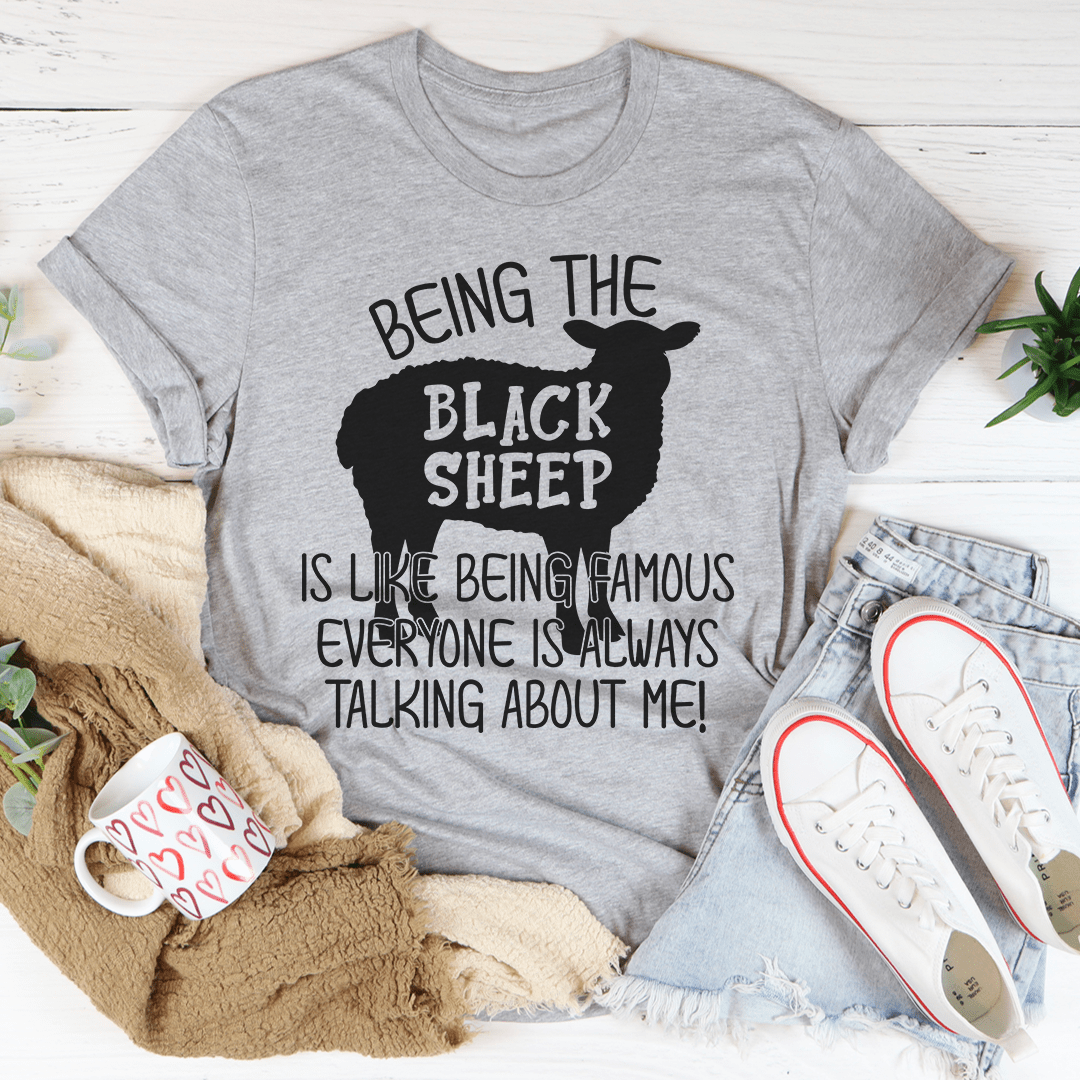 A stylish black t-shirt featuring the phrase 'Being The Black Sheep Is Like Being Famous' printed in bold letters, showcasing its soft fabric and durable stitching.