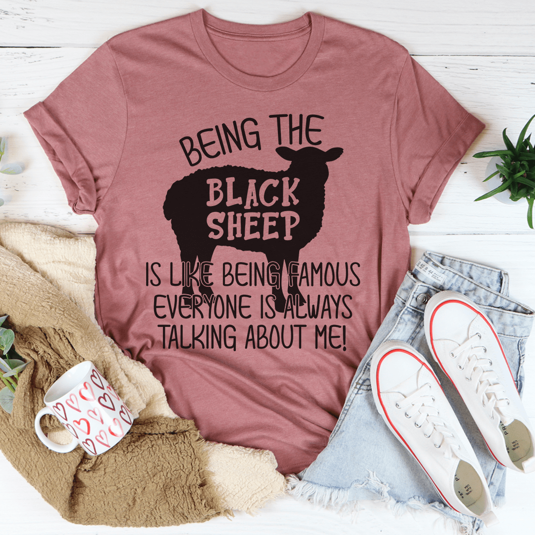 A stylish black t-shirt featuring the phrase 'Being The Black Sheep Is Like Being Famous' printed in bold letters, showcasing its soft fabric and durable stitching.